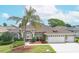 Beautiful one-story home with a three-car garage, manicured lawn, and a majestic palm tree in the front yard at 13942 Talmage Loop, Hudson, FL 34667
