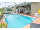 A view of the pool with an outdoor bar and seating under a screened-in lanai at 13942 Talmage Loop, Hudson, FL 34667
