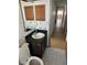 Bathroom with a toilet, vanity, sink, mirror, and wood look flooring leading down a hallway at 1412 Wexford N Dr, Palm Harbor, FL 34683