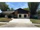 Charming single-story home with a brick accent wall, black trim, and a large concrete driveway leading to a two-car garage at 1412 Wexford N Dr, Palm Harbor, FL 34683