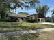 Well-maintained lawn with mature trees frames a charming single-story home with a brick chimney and two-car garage at 1412 Wexford N Dr, Palm Harbor, FL 34683