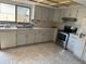 Traditional kitchen featuring white cabinets, stainless steel appliances, and a double sink under a bright window at 1412 Wexford N Dr, Palm Harbor, FL 34683