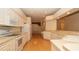 A well-lit kitchen featuring white appliances and cabinets, with laminate floors and plenty of counter space at 15038 Tamarind Loop, Spring Hill, FL 34609