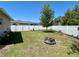 Backyard with a privacy fence, a young shade tree, green grass, and a star-shaped fire pit at 15585 Rene Ct, Brooksville, FL 34604