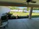 A covered patio with a ceiling fan looks out to a backyard with a privacy fence and simple landscaping at 15585 Rene Ct, Brooksville, FL 34604