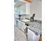 A compact kitchen featuring tile floors, white cabinets, and essential appliances including a range, microwave, and refrigerator at 1881 Mazo Mnr # I-6, Lutz, FL 33558