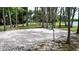 Sandy volleyball court featuring a net, set among tall trees with a glimpse of the lake in the background at 1916 & 1910 Beachway Ln, Odessa, FL 33556