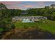 Expansive aerial view of the property, showcasing the pool, tiki hut, pond, and surrounding landscape at 2400 Commack Ct, New Port Richey, FL 34655