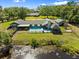 Aerial view of a private backyard oasis featuring a pool, Tiki hut, and mature trees at 2400 Commack Ct, New Port Richey, FL 34655