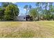 View of a large grassy backyard area, including a chicken coop and a small storage shed at 2400 Commack Ct, New Port Richey, FL 34655