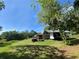 This image shows a lush green yard with a trailer, shed, and a tree with hanging moss at 2400 Commack Ct, New Port Richey, FL 34655