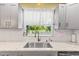 Kitchen with stainless steel sink, faucet, granite countertops, white backsplash, and serene backyard view at 2400 Commack Ct, New Port Richey, FL 34655