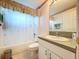 Traditional bathroom featuring a tub/shower combo with white tiling and vanity with a solid surface countertop at 3054 Oakbrook Cir, Clearwater, FL 33759