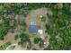 Aerial view of secluded property featuring a pool, fire pit, and a home surrounded by dense trees at 3355 La Vista St, Brooksville, FL 34604