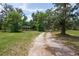 A long, winding driveway leads to a secluded home surrounded by mature trees and a lush landscape at 3355 La Vista St, Brooksville, FL 34604