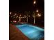 Backyard pool and spa illuminated by string lights and a fire pit in the background at nighttime at 3555 Bracknell Ct, Land O Lakes, FL 34638