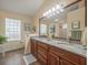 Bathroom vanity with double sinks, granite countertop, decorative lighting and ceramic tile flooring at 446 Romine Ct, Spring Hill, FL 34609