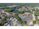 Aerial view showcases a community with a pool, tennis courts, lake, and mature landscaping at 4837 Prince George Cir, New Port Richey, FL 34655