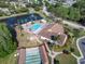 Aerial view of the community pool, clubhouse, and shuffleboard courts near a scenic pond at 4837 Prince George Cir, New Port Richey, FL 34655