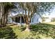 White home exterior featuring a screened-in porch and lush backyard with mature trees providing shade at 4837 Prince George Cir, New Port Richey, FL 34655