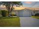 Charming single-story home with a well-maintained lawn and attached one car garage at sunset at 5106 Blue Heron Dr, New Port Richey, FL 34652