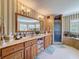 This bright bathroom features a double vanity, neutral tile, and a glass enclosed shower at 5198 Legend Hills Ln, Brooksville, FL 34609