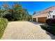 A long, brick-paved driveway leads to a spacious two-car garage, set amidst lush landscaping at 5198 Legend Hills Ln, Brooksville, FL 34609