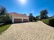 Wide brick driveway leading to a two-car garage surrounded by lush greenery, enhancing curb appeal at 5198 Legend Hills Ln, Brooksville, FL 34609