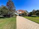 Inviting home with a long paved driveway leading to the residence, framed by mature trees and lawn at 5198 Legend Hills Ln, Brooksville, FL 34609