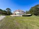 Rear exterior of a home featuring a sprawling lawn, patio, and a charming garden area at 5198 Legend Hills Ln, Brooksville, FL 34609