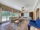 Bright living room with large windows, comfortable seating, and a decorative ceiling fan at 5198 Legend Hills Ln, Brooksville, FL 34609