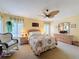 Cozy main bedroom showcasing floral bedding, a ceiling fan, and sunny windows at 5198 Legend Hills Ln, Brooksville, FL 34609