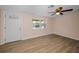 Bright living room features a ceiling fan, wood-look flooring, and a large window, creating a welcoming atmosphere at 7321 Parrot Dr, Port Richey, FL 34668