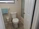 This bathroom has a white toilet, gray wood floor and a frosted shower door at 7508 Cypress Knee Dr, Hudson, FL 34667