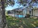 View of screened in pool area and lush green yard from under mature trees at 7508 Cypress Knee Dr, Hudson, FL 34667