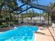 Inviting screened-in pool area with clear blue water and lounge chairs in a fenced yard at 7508 Cypress Knee Dr, Hudson, FL 34667