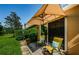 Exterior view of patio with chairs, sunshade, and green landscaping at 8604 Corinthian Way, New Port Richey, FL 34654