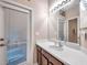 Bright bathroom with a large mirror, white countertop, wood cabinets and a door to the outside at 8635 Creedmoor Ln, New Port Richey, FL 34654