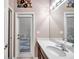 Bright bathroom featuring a door to the outside, a large mirror, white countertop, and wood cabinets at 8635 Creedmoor Ln, New Port Richey, FL 34654
