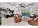 Open-concept living room with modern kitchen view, comfortable seating, and access to the outdoor patio at 8945 Bella Vita Cir, Land O Lakes, FL 34637