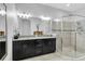 Luxurious main bathroom features dual sinks, granite countertops, dark wood cabinets, and a glass shower at 8945 Bella Vita Cir, Land O Lakes, FL 34637