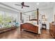 Comfortable main bedroom features a four-poster bed, hardwood floors, tray ceiling, and lots of natural light at 8945 Bella Vita Cir, Land O Lakes, FL 34637