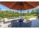 Outdoor seating area with wrought iron table under an umbrella, overlooking the lake at 8945 Bella Vita Cir, Land O Lakes, FL 34637
