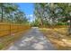 Long driveway entrance to the property, lined with a wooden fence and scattered mature trees at 9078 Birmingham Ave, Weeki Wachee, FL 34613