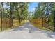 Gated driveway leading to the residence, flanked by mature trees and a wooden fence at 9078 Birmingham Ave, Weeki Wachee, FL 34613