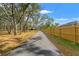 Long driveway leading to the house, bordered by a wooden fence and lush trees at 9078 Birmingham Ave, Weeki Wachee, FL 34613