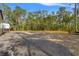 Large gravel parking lot features a metal building, surrounded by trees, offering ample space for outdoor activities at 9078 Birmingham Ave, Weeki Wachee, FL 34613