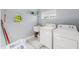 Bright laundry room with white washer, dryer, utility sink, and overhead shelving at 9078 Birmingham Ave, Weeki Wachee, FL 34613