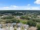 An aerial view showcasing the neighborhood homes surrounded by mature trees and community amenities in the distance at 9104 Water Hazard Dr, Hudson, FL 34667