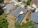 An aerial view of a home showcasing a screened pool with a brick deck, mature landscaping and residential street access at 9104 Water Hazard Dr, Hudson, FL 34667